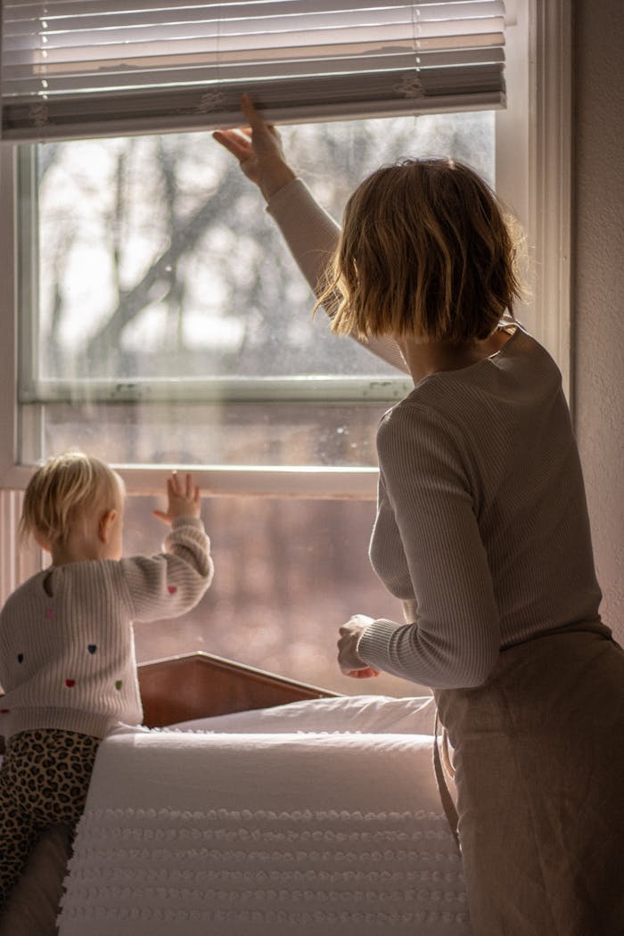 A mother and child enjoying natural light through a modern window in a cozy home setting.